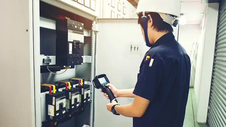 Técnico inspecionando um painel elétrico com uma câmera termográfica